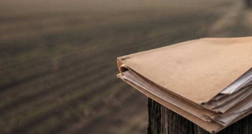 Worker records folder on a fence post representing H-2A back wage documentation